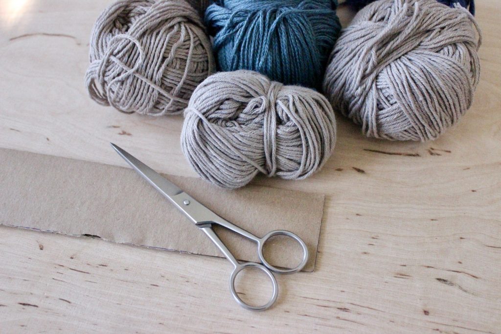 Benötigtes Material: Wollreste, Schere, Pappkarte